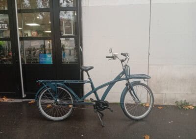 Vélo cargo électrique devant atelier robuste, mobilité durable et vélo urbain écologique.
